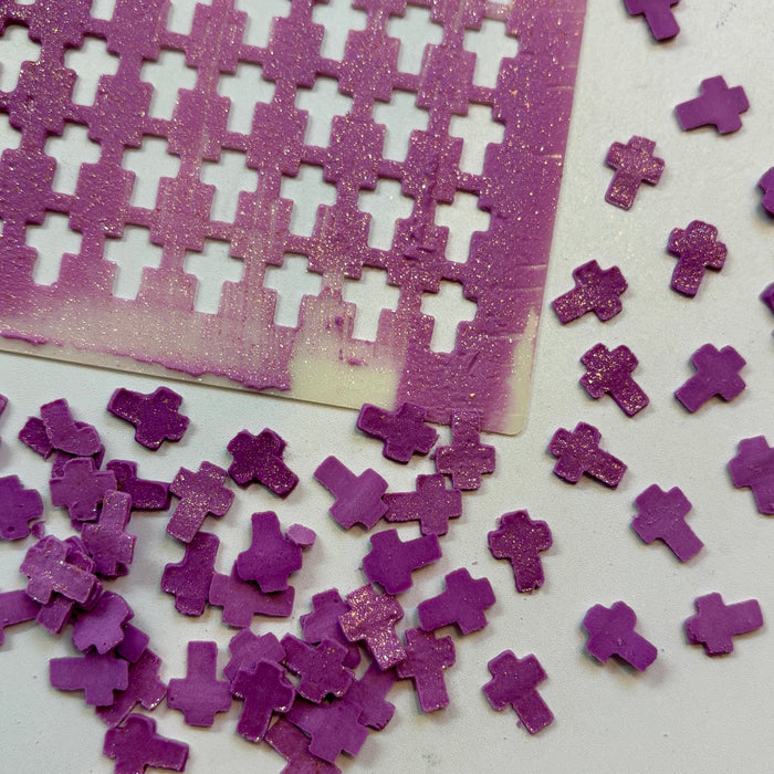 Cross Sprinkles Stencil shown with the cross sprinkles made in purple royal icing and spread with gold edible glitter