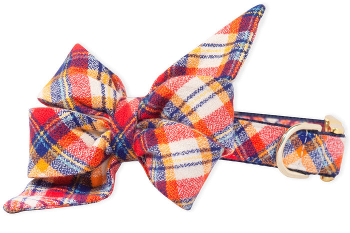 Dog collar featuring a matching, large double-layered belle bow in a bold plaid pattern perfect for a fall stroll. The pointed, feminine belle bow tips are exaggerated for a dramatic look, and the collar has a  metal buckle and D-ring for leash attachment.
