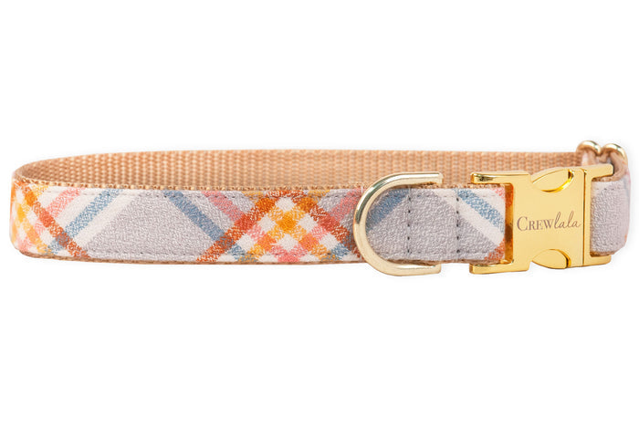 A dog collar made of soft flannel pastel plaid fabric featuring diagonal stripes. The collar has a tan nylon backing, a metal D-ring for leash attachment, and metal side-release buckle engraved with the brand name “Crewlala.”