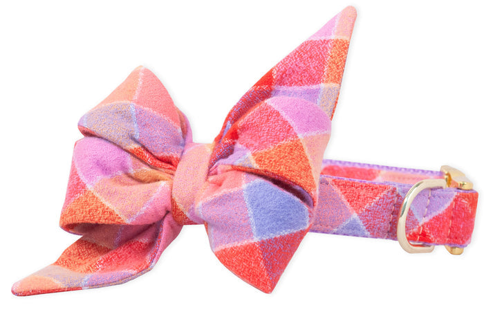 Dog collar with an oversized feminine belle bow in soft flannel, featuring a pastel plaid pattern. The layered belle bow has long pointed tails and is attached to a coordinating collar with a metal D-ring and buckle.