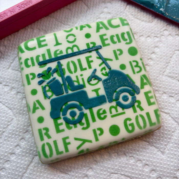 A square cookie airbrushed in green with our Golf Talk Cookie Stencil and then decorated with our Golf Cart Cookie Stencil in blue royal icing, BakeArt Stencils