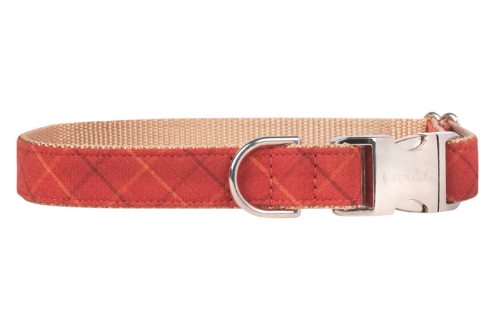 Rust-red dog collar with a warm orange plaid grid pattern, nylon webbing interior, and polished hardware engraved with Crewlala.