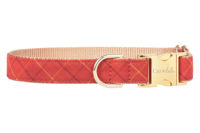 Rust-red dog collar with a warm orange plaid grid pattern, nylon webbing interior, and polished hardware engraved with Crewlala.